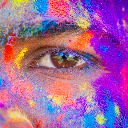Close up of an eye covered in colored dye at Holi festival in Jaipur, India.